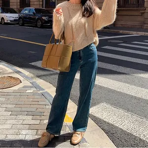 Street style view of a chunky beige cable-knit round neck sweater for autumn fashion