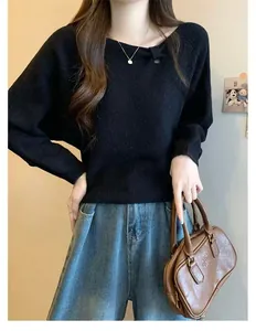 Close-up detail of black asymmetrical neckline sweater with elegant pleats and cutouts.