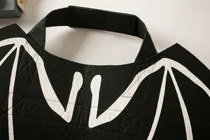Detail view of black felt pet bat wings with white vein print and velcro strap.
