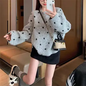 Primo piano di un maglione grigio vintage a pois indossato da una modella in un interno