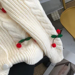 Close-up of white chunky knit cardigan with cute cherry appliques