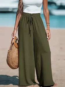 Full-body view of olive green wide-leg trousers with drawstring waist on sunny beach