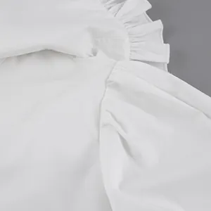 Detail of white doll collar shirt showing ruffled shoulder and cotton texture.