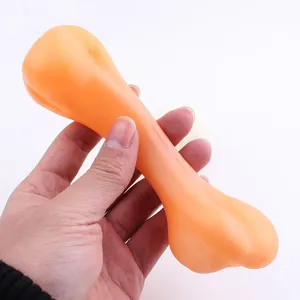 Hand holding a durable orange vinyl squeaky bone toy for dog training and play activity.
