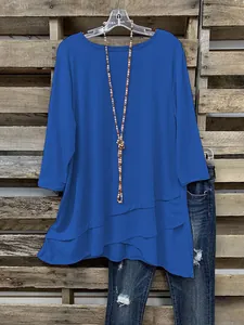 Detailopname van een casual blauwe damestuniek met een asymmetrische gelaagde zoomlijn