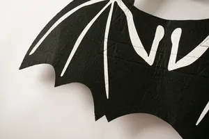 Close-up detail of black felt material and white skeletal print on bat wing pet costume