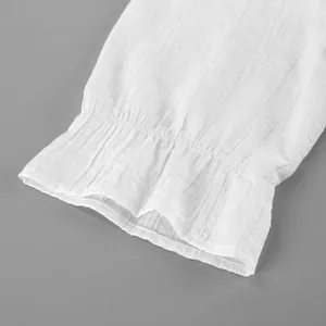 Détail en gros plan montrant la manche élastique à volants blancs et le tissu texturé
