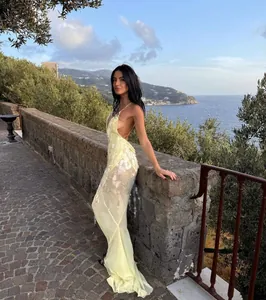 Side view of a pale yellow backless mermaid dress with sequins in a coastal setting.
