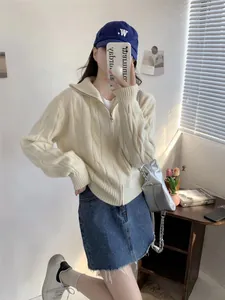 Detailed view of a cream cable-knit double-zipper cardigan styled with a denim skirt