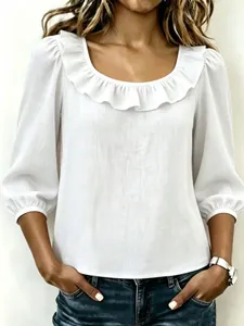 Detail van een witte blouse met elegante ruffelhals en textuurdetails van de stof
