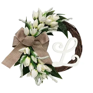 Detailed view of handmade tulip wreath with burlap bow and cursive white letter L ornament