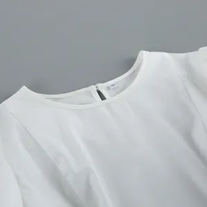 Detailopname van een elegante witte blouse met ronde hals, maatlabel XS en knoopdetail