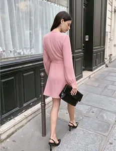 Detalle de vestido cruzado rosa con escote en V, mangas abullonadas y lazo en cintura