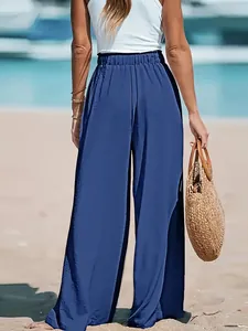 Detailed back view of women's comfortable blue wide-leg pants on a sunny beach setting