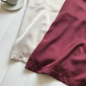 Primo piano dettagliato che mostra la trama liscia del tessuto satinato dei top bianco e bordeaux