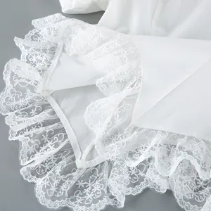 Detailopname van de verfijnde witte bloemenkant op een elegante Franse blouse.