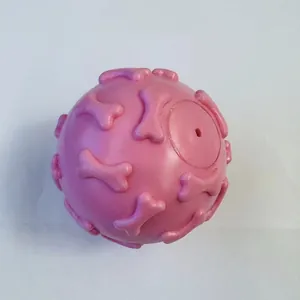 Detailed view of pink TPR squeaky dog ball with raised bone patterns for dental care.