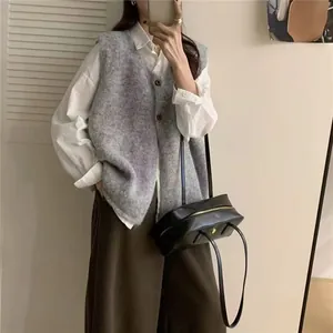 Gilet oversize in maglia grigia con camicia bianca e borsa in pelle nera dettaglio.