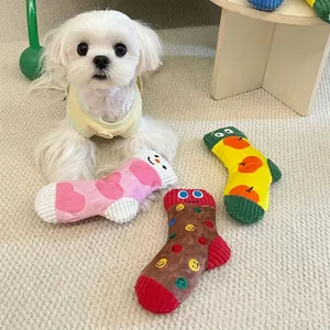 Close-up of colorful sock-shaped plush squeaky toys for dogs on a beige carpet.