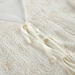 Dettaglio di un top da vacanza in pizzo jacquard color crema con elegante lacci frontali