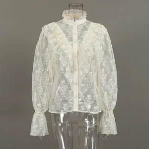 Elegante cremefarbene Spitzenbluse mit Rüschen und Trompetenärmeln am Schaufensterpuppe.