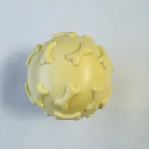 Detailed macro view of a durable yellow TPR squeaky dog toy ball with 3D bone patterns
