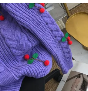 Close-up of purple knit cardigan with 3D cherry applique and cable stitch details