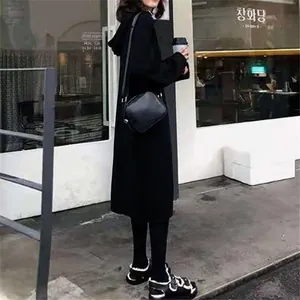 Full body view of a cozy oversized hooded knitted sweater dress in a street setting