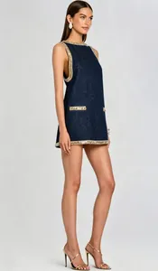 Detailed side view of a navy denim mini dress with gold rhinestone trim and gold stiletto heels.