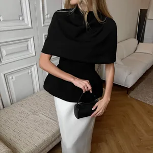 Détail du haut cape noir élégant avec une jupe longue blanche pour un look chic raffiné