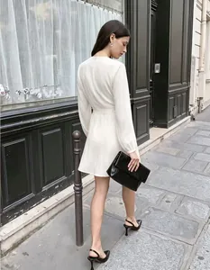 Elegante vestido cruzado blanco con mangas abullonadas y lazo en una calle de París
