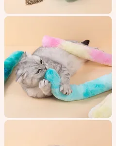 Graue Katze spielt mit einem langen Regenbogen-Plüschkissen mit Katzenminze