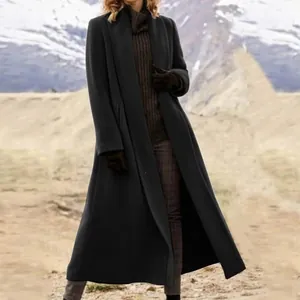 Elegante abrigo largo de lana negra para mujer usado en un paisaje de montaña frío