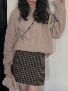 Détail d'un pull vintage oversize à col rond porté avec une mini-jupe à carreaux