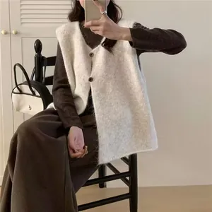 Dettaglio ravvicinato di un gilet in maglia senza maniche bianco con bottoni marroni