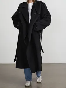 Professional full-length view of a black double-breasted long trench coat on a model.