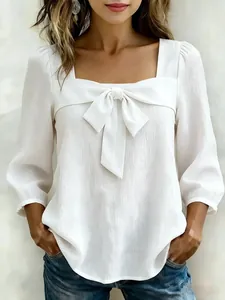 Detail der weißen Bluse mit quadratischem Ausschnitt, großem Bogen und strukturierter Stoff