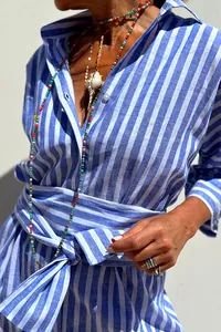 Detail of blue and white striped shirt dress with belted waist and beads.