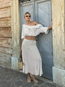 Femme en crop top blanc à volants épaules dénudées et jupe longue en dentelle