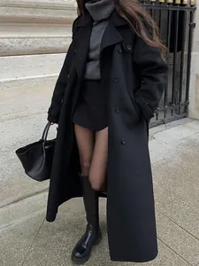 Elegant long black double-breasted coat with professional styling and a black handbag