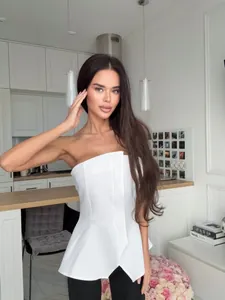 Detailansicht eines weißen trägerlosen Schößchen-Tops mit asymmetrischem Schlitz.