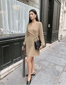 Elegante vestido cruzado beige con cuello en V y mangas abullonadas en un entorno urbano chic.