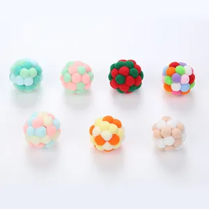 Colorful handmade pom-pom cat toy balls in various festive and pastel color patterns