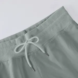 Detailed view of elastic waistband and adjustable drawstring on sage green wide-leg pants
