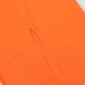 Macro detail view of vibrant neon orange ribbed knit fabric showing slit construction