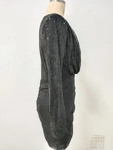 Detailed side profile of a black sequined ruched evening dress with long sleeves.