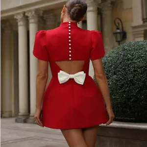 Vista posteriore di un mini abito rosso con schiena scoperta fiocco bianco e bottoni perla