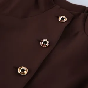Detail macro view of decorative gold embossed buttons on vintage brown dress fabric.