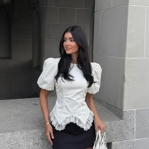 Detailweergave van een elegante witte blouse met pofmouwen, kant en een getailleerd model