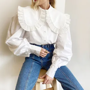 Close-up detail of a white cotton shirt featuring a large ruffle doll collar and puff sleeves.